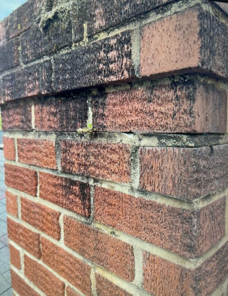 Close-up image showing a damaged brick chimney with water and smoke stains.